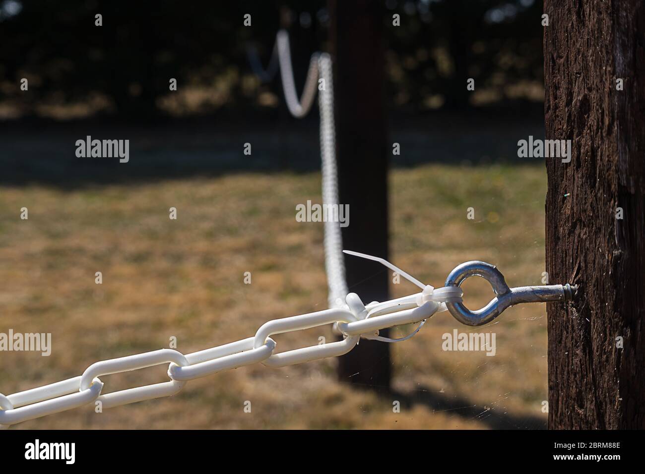 boulon à bascule dans le montant de clôture en bois avec maillons de chaîne  blancs en boucle dans un champ herbacé Photo Stock - Alamy