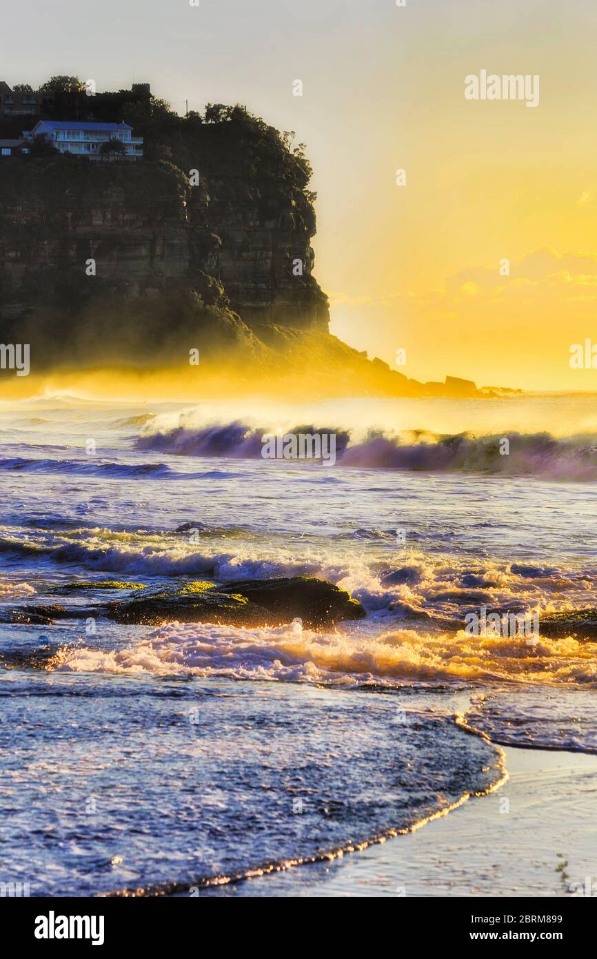 Bungan tête de rochers de grès avec maison résidentielle au bord de la falaise au-dessus des vagues interminables de l'océan Pacifique au lever du soleil. Banque D'Images