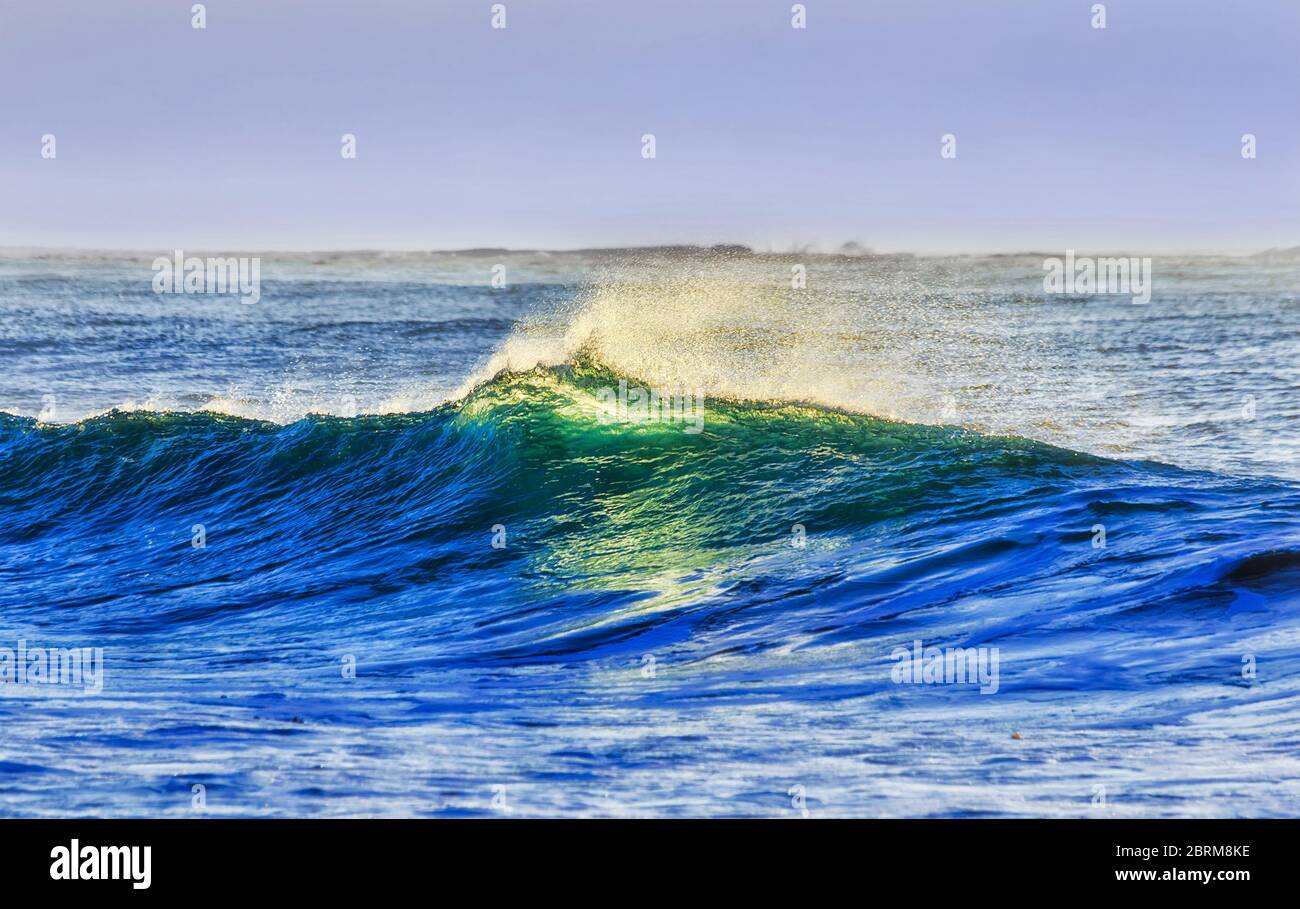 Montée en vague sur la plage de Bungan, sur les plages du nord de Sydney, au lever du soleil, avec reflet coloré de la surface. Banque D'Images