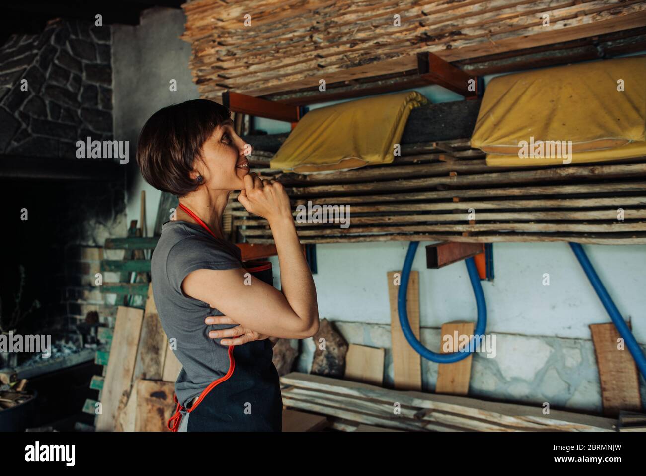 Craftswoman dans un atelier de menuiserie regardant le bois scié Banque D'Images