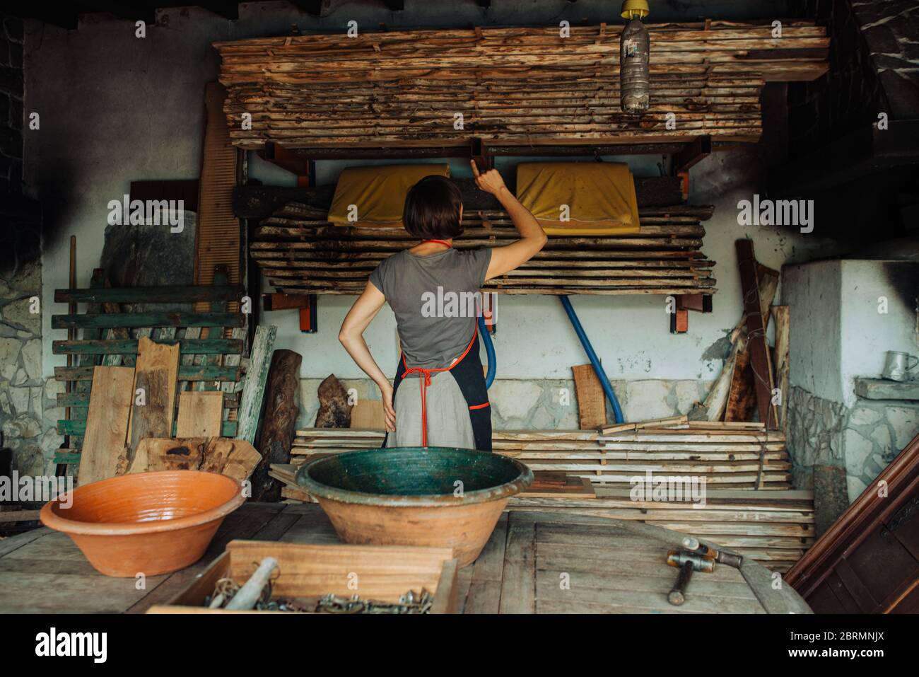 Femme debout dans un atelier de menuiserie comptant des pièces en bois Banque D'Images