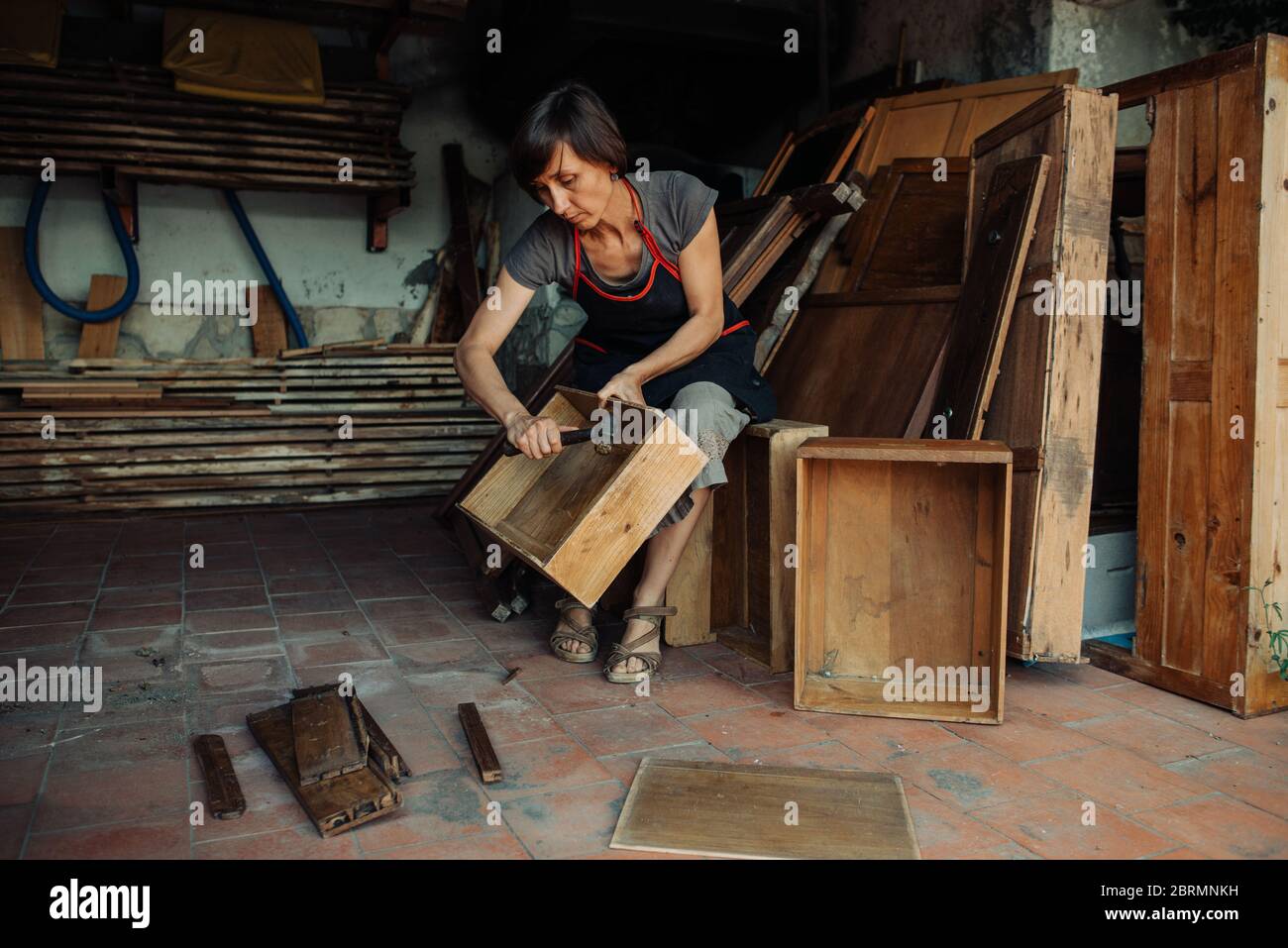 Artisan féminin brisant de vieux meubles en bois pour réutilisation artistique Banque D'Images