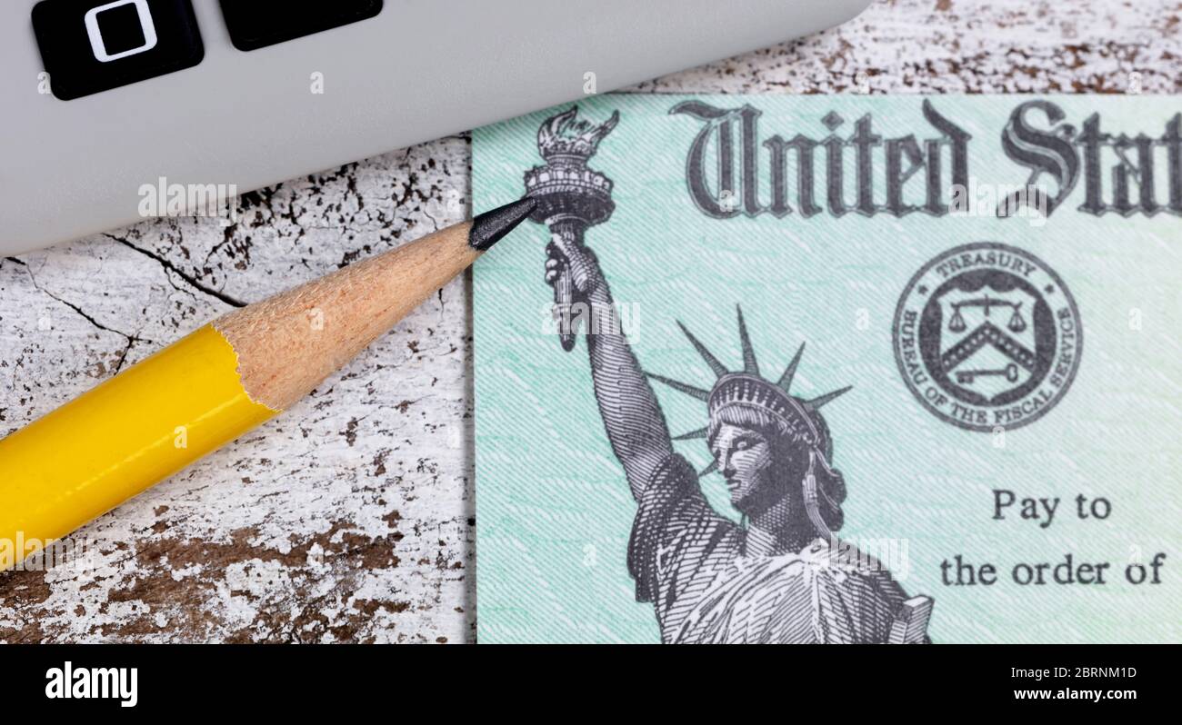 Gros plan de la pointe du crayon avec le chèque de remboursement des impôts du gouvernement et la calculatrice en arrière-plan Banque D'Images