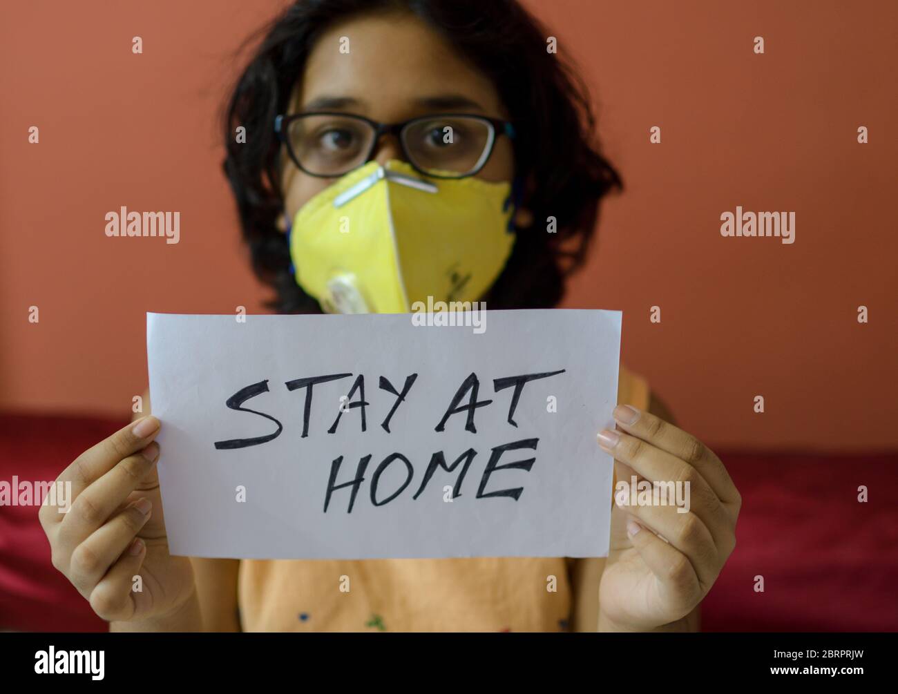 Une fille tenant un message de quarantaine « à la maison » pour combattre la pandémie COVID-19 Banque D'Images