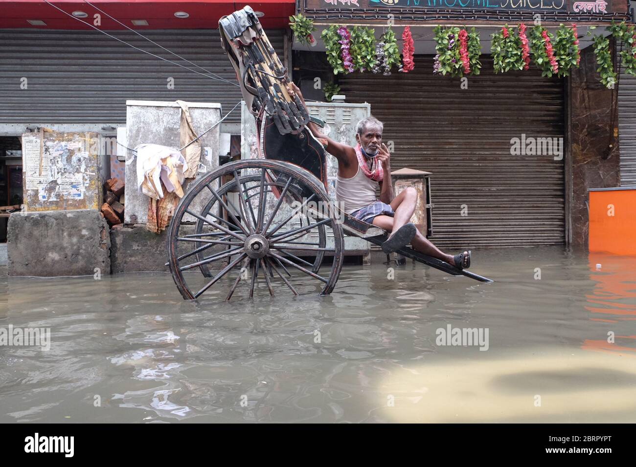 Un extracteur de pousse-pousse à main attendait les clients dans une voie submergée après les fortes pluies dues à la tempête cyclonique Super Amphan. Au moins 72 personnes ont perdu la vie au Bengale occidental à cause du cyclone Amphan, selon les médias locaux rapportés. Les pluies et les vents violents ont également causé des dommages considérables aux cultures et aux infrastructures à Odisha. La connectivité et l'alimentation Internet sont restées un défi après le cyclone. Une équipe du ministère de l'intérieur de l'Union se rendra dans les États pour évaluer les dommages causés par le cyclone. (Photo de Satyajit Shaw/Pacific Press) Banque D'Images