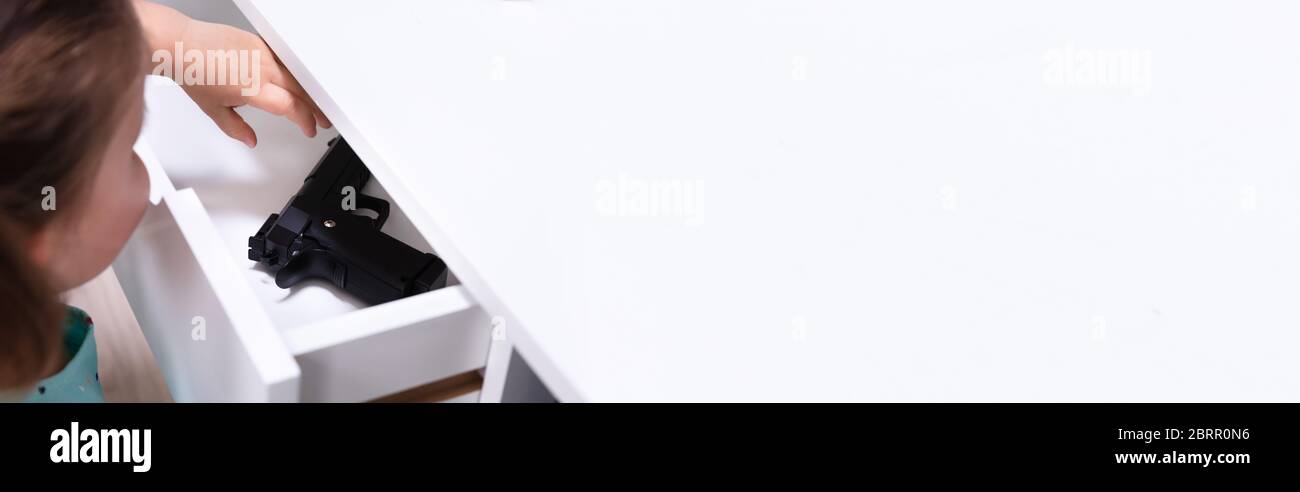Enfant fille prenant pistolet de tiroir. Sécurité à domicile Banque D'Images