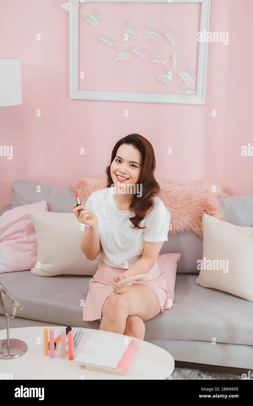 Beauty blogger avec rouge à lèvres, miroir et l'enregistrement de caméra vidéo tutoriel maquillage à la maison Banque D'Images