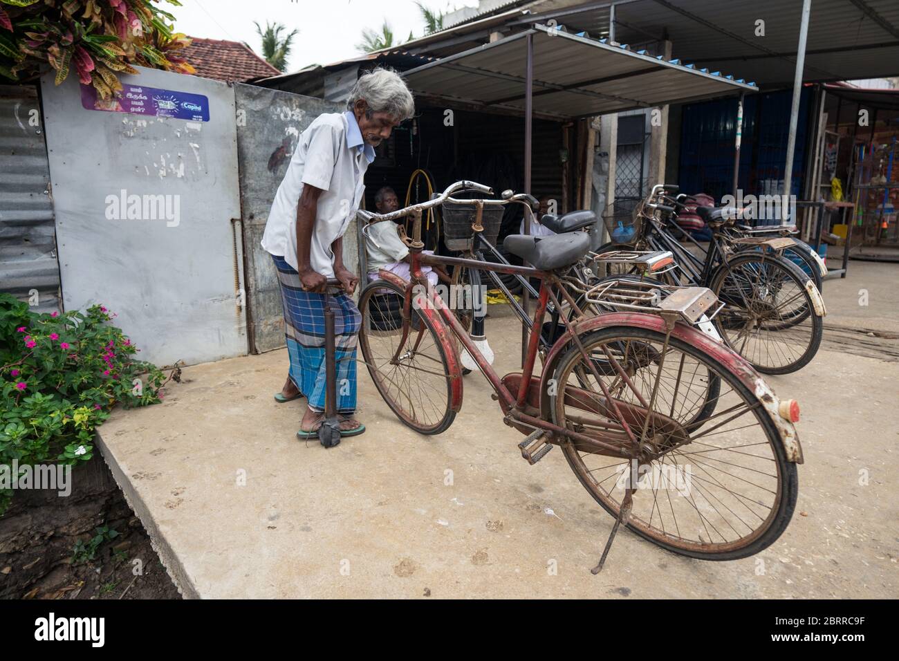 Jaffna / Sri Lanka - 15 août 2019 : homme âgé à cheveux blancs gonflant la roue de vélo avec un gonfleur à pied Banque D'Images
