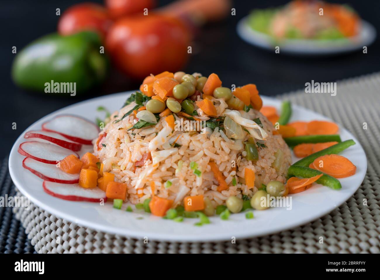 Plat avec riz et légumes, décoré de tranches de carottes et de radis et de bandes de piment. Banque D'Images