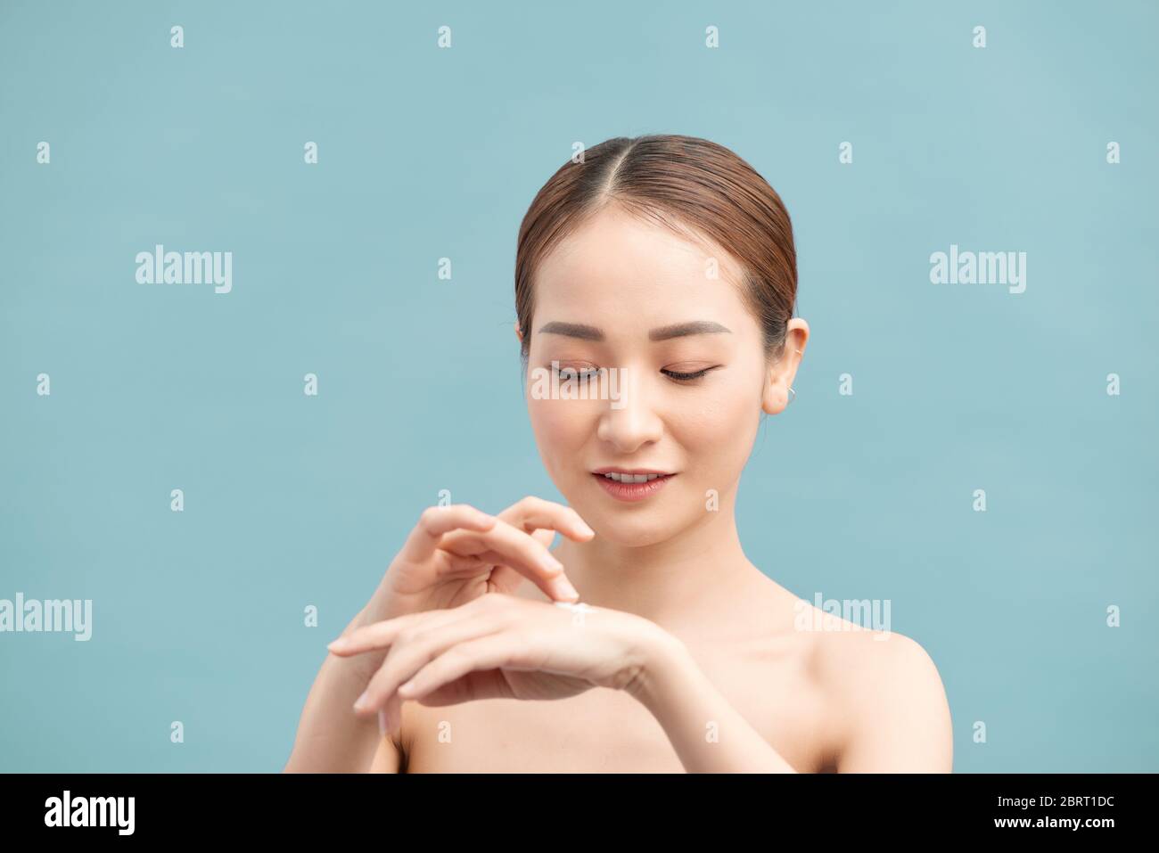 Femme heureuse hydratant les mains peau avec crème hydratante sur fond violet Banque D'Images