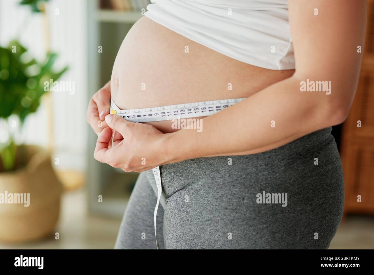 Femme enceinte utilisant un mètre ruban pour contrôler l'abdomen Banque D'Images
