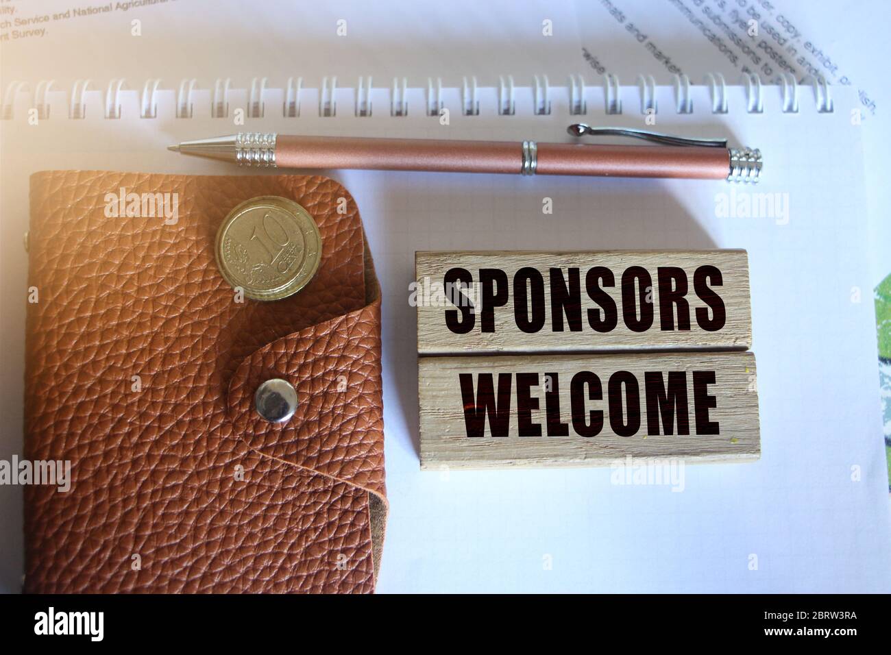 Les sponsors sont les bienvenus sur des blocs de bois, un stylo portefeuille et des pièces. Concept de parrainage de collecte de fonds Banque D'Images