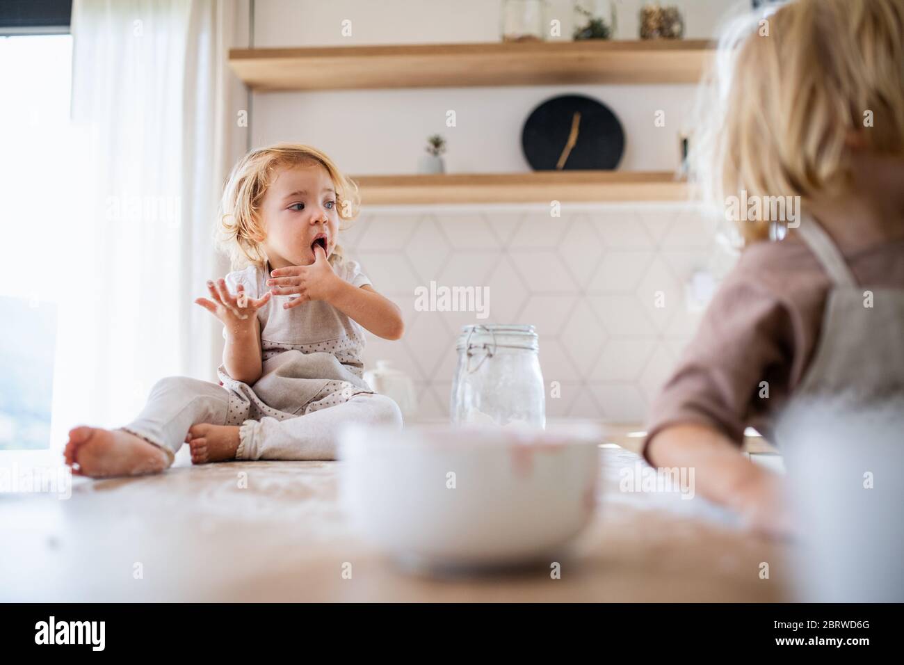 Deux petits enfants aidant à l'intérieur dans la cuisine avec la cuisine. Banque D'Images