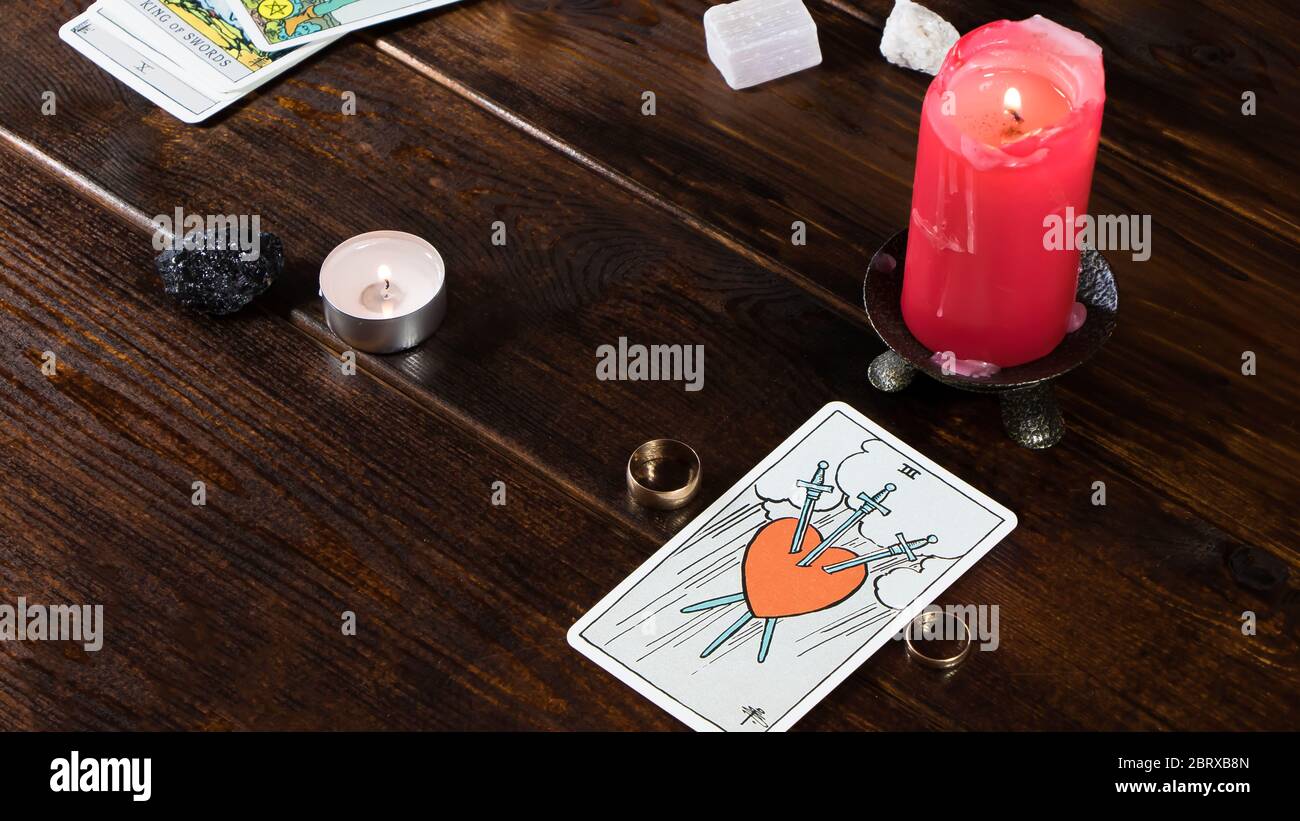 New York, USA-19.05.2020: Des anneaux de mariage avec des cartes de fortune, des bougies allumées et des pierres magiques sont sur la table. La chance de dire pour l'amour sur le rel Banque D'Images