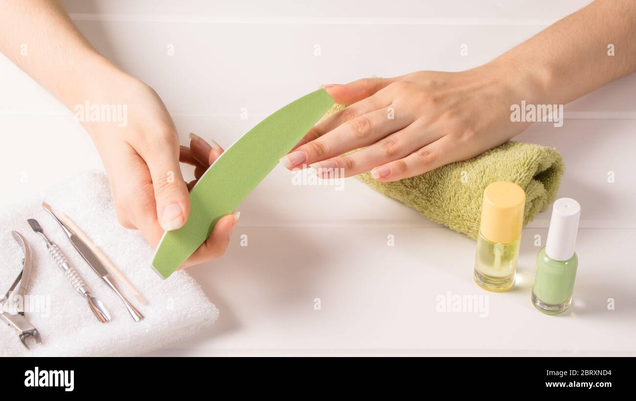 Manucure. Une femme limes ses ongles. Raccourcir les clous longs. Outils de manucure. Soins des ongles à domicile, SPA, beauté. Ongles naturels longs. Salon de beauté. Banque D'Images