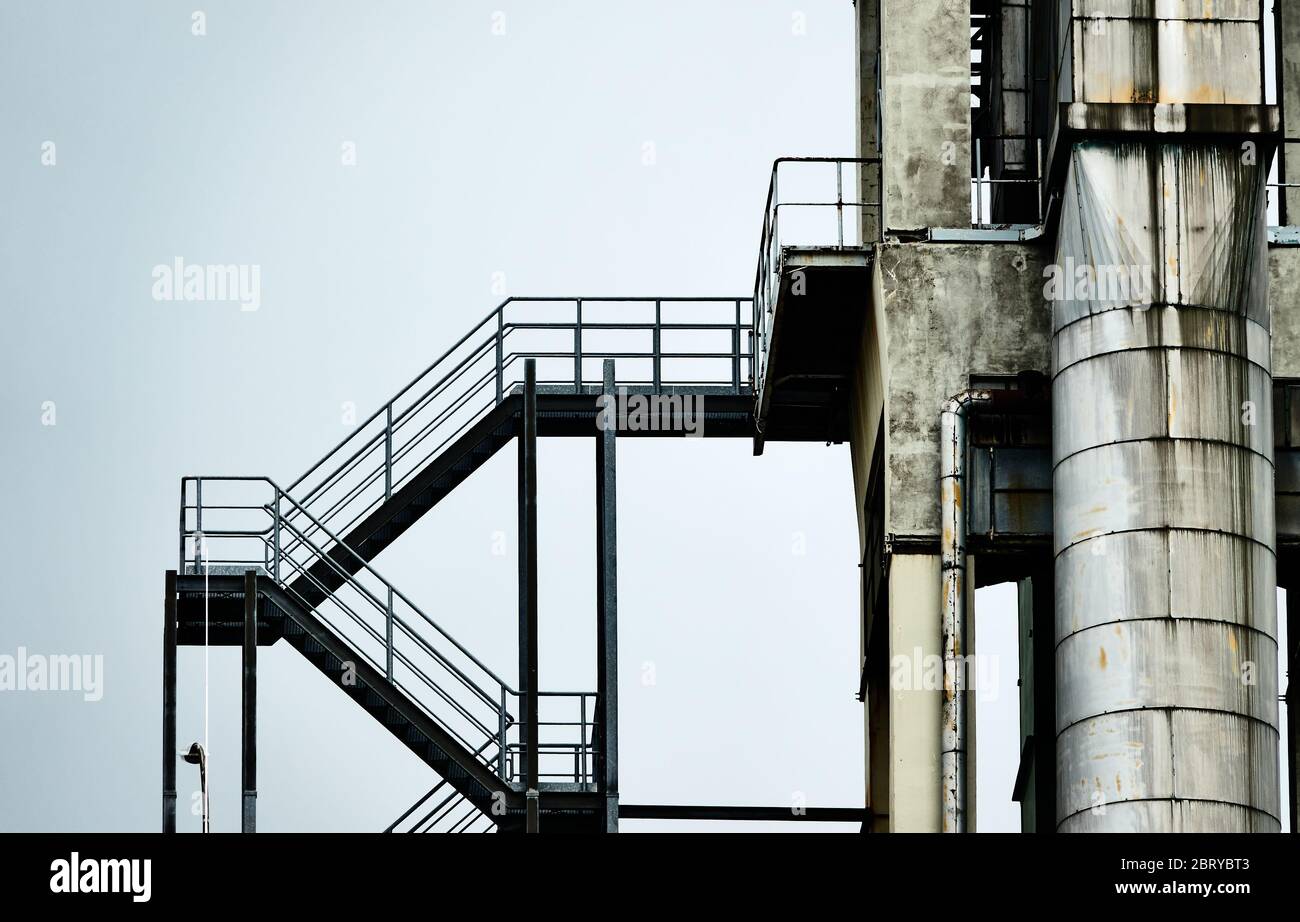 Résumé image incolore d'un escalier en fer à côté d'un tuyau en aluminium à la tour d'une usine industrielle Banque D'Images