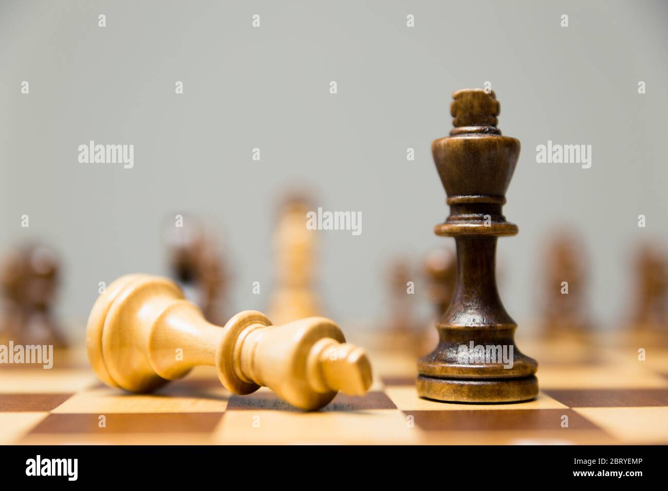 Deux pièces d'échecs sur un échiquier de la légère, couché sur le côté au pied de la victorieuse en bois le roi Banque D'Images