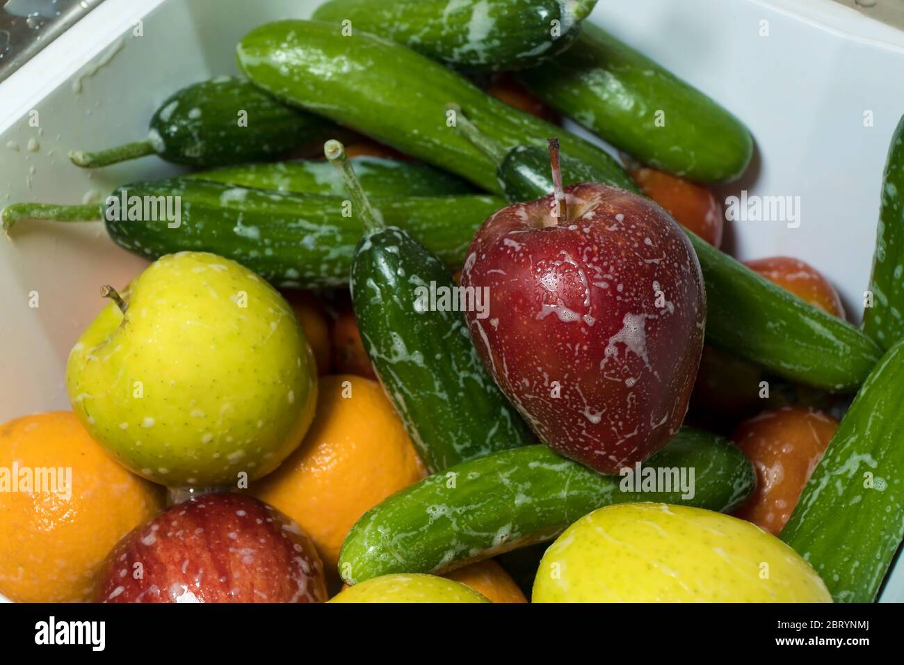 Pommes fraîches savonnantes concombres et oranges dans la cuisine Banque D'Images