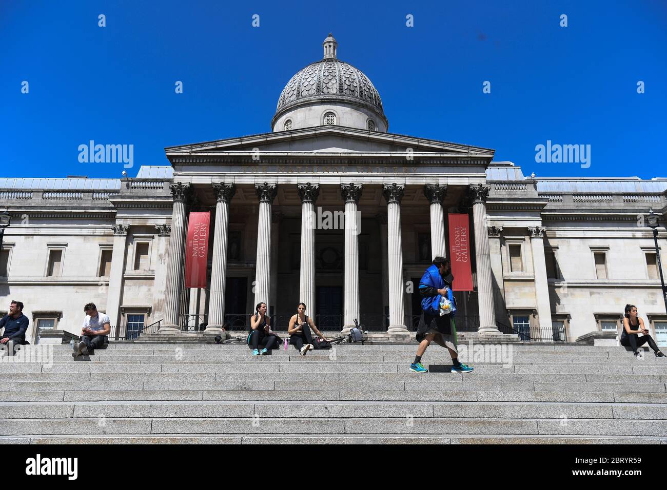 Les gens s'assoient sur les marches au soleil à Trafalgar Square, Londres, après l'introduction de mesures pour sortir le pays de son isolement. Banque D'Images