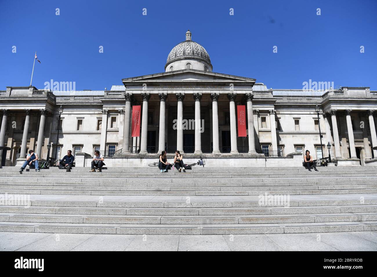 Les gens s'assoient sur les marches au soleil à Trafalgar Square, Londres, après l'introduction de mesures pour sortir le pays de son isolement. Banque D'Images