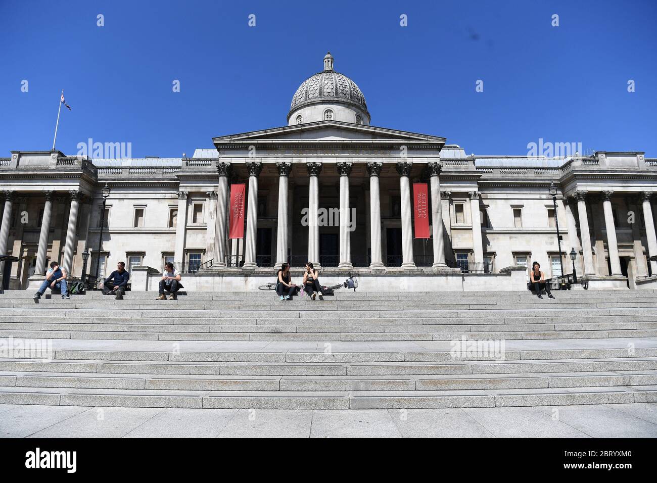 RETRANSMETTANT LA DATE DE MODIFICATION les gens sont assis sur les marches au soleil à Trafalgar Square, Londres, après l'introduction de mesures pour mettre le pays hors de l'isolement. Banque D'Images