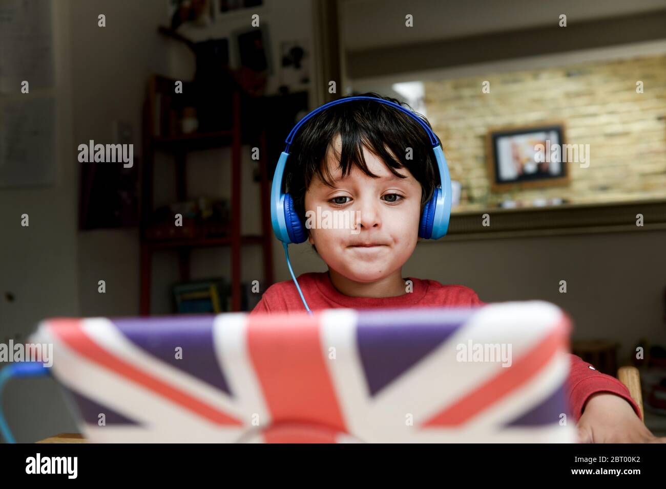 Un garçon de cinq ans dans un casque bleu ayant une session d'apprentissage interactive, l'école à domicile. Banque D'Images