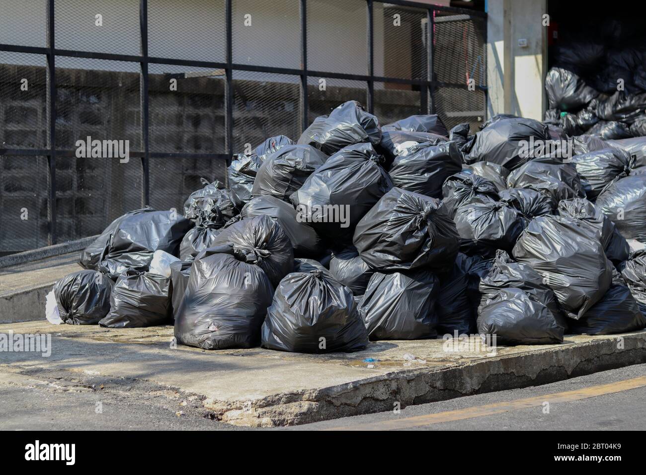 Sacs noirs qui mettent les déchets à l'intérieur et nouent la pile de sacs au point de collecte des déchets. Banque D'Images