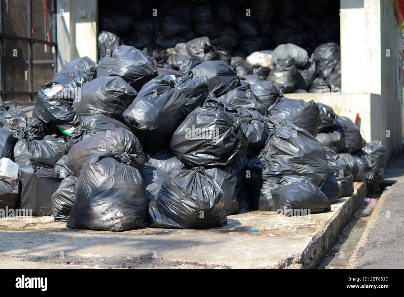 Sacs noirs qui mettent les déchets à l'intérieur et nouent la pile de sacs au point de collecte des déchets. Banque D'Images