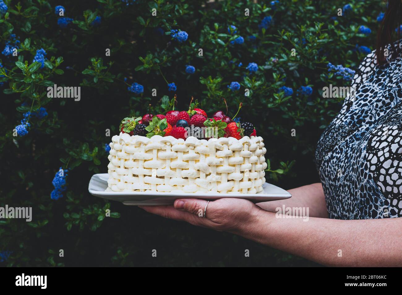 Femme Tenant Une Assiette Avec Un Magnifique Gateau D Ete Decore De Baies Sur Fond Fleuri Photo Stock Alamy