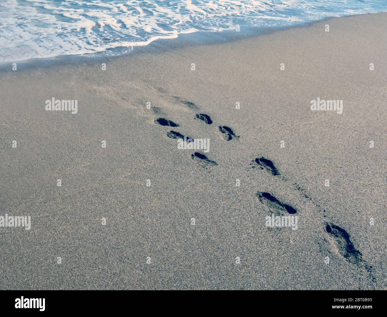 Empreintes de pas sur la plage menant à l'eau Banque D'Images