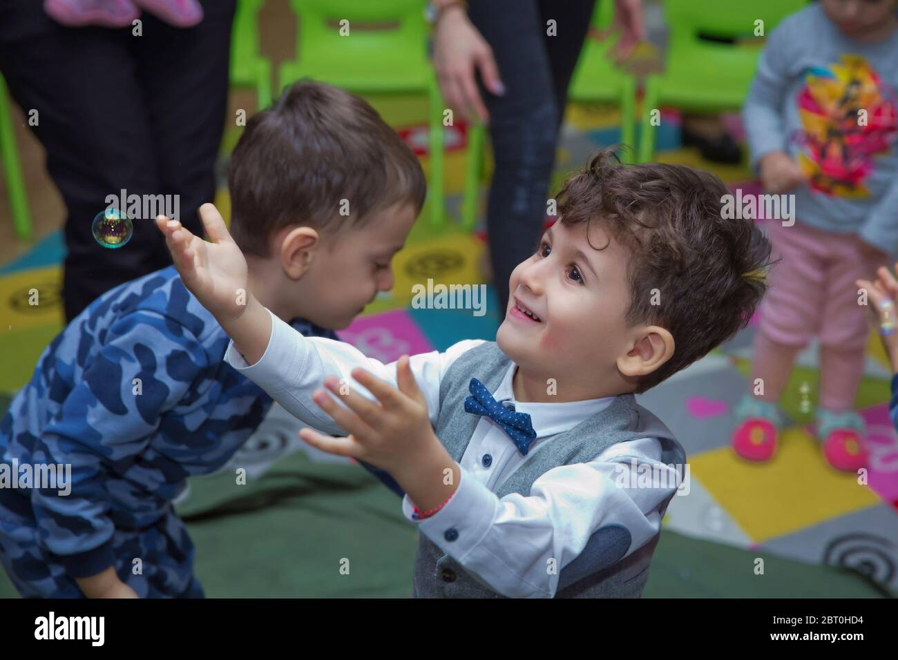 Joli petit garçon attrapant des bulles de savon . Petit garçon blond jouant avec des bulles de savon . Enfants à la fête. Des bulles de savon apparaissent. Fête d'enfants. À Banque D'Images