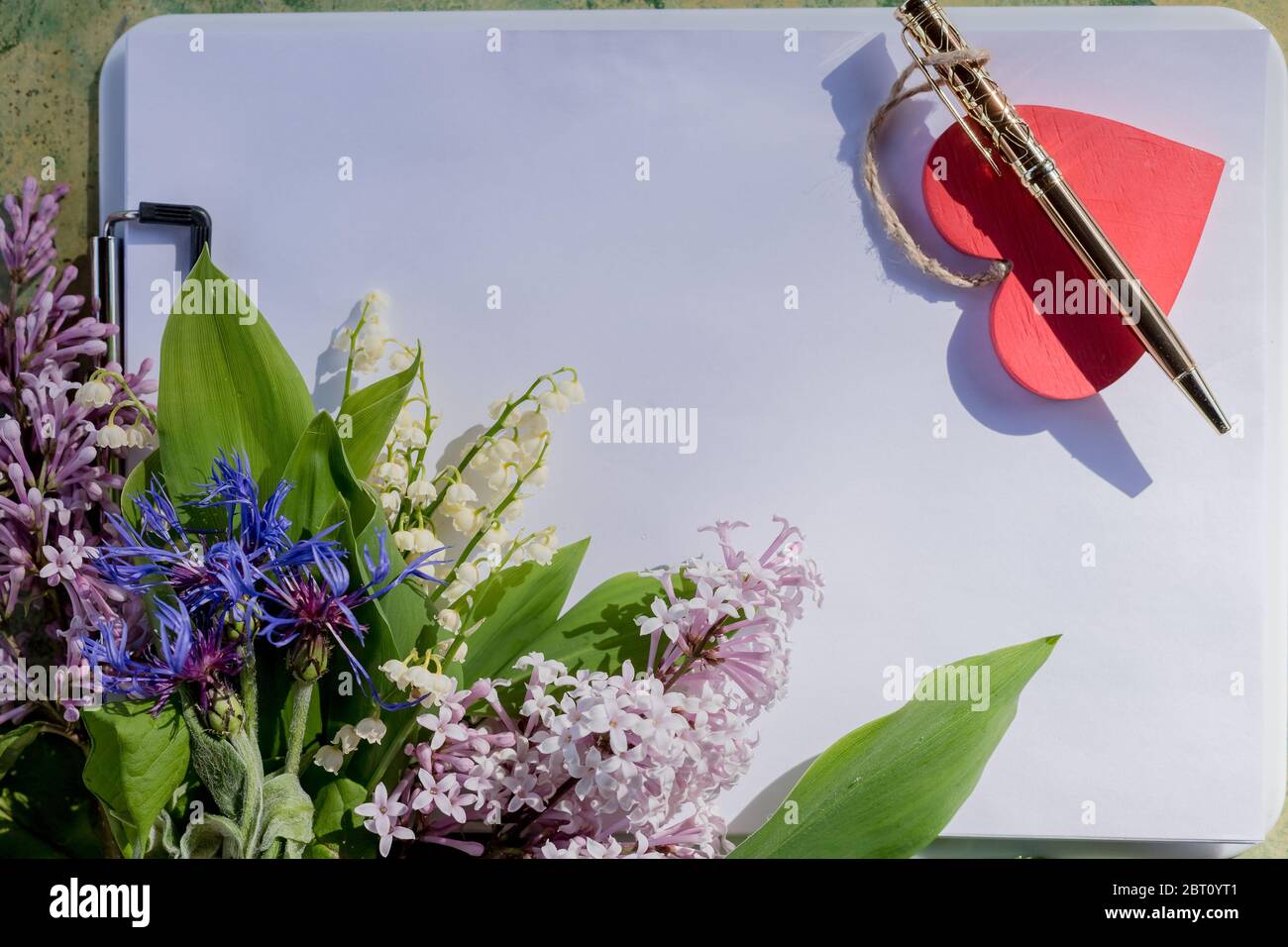 Anniversaire, mère, Valentines, femmes, concept de mariage.UN bouquet de fleurs de printemps pourpres, blanches, un Bloc-notes pour écrire sur un printemps et un lilas Banque D'Images