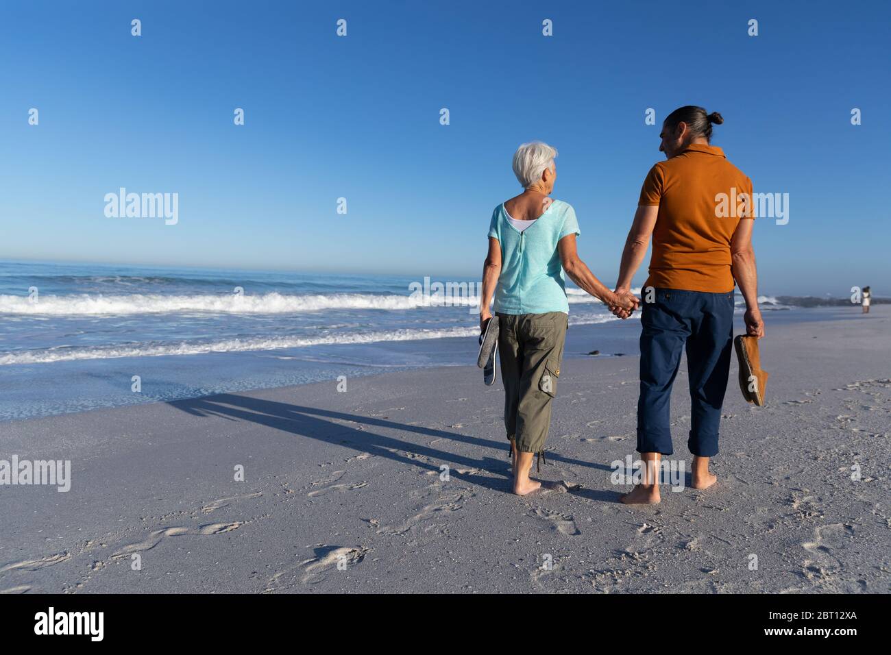 Couple caucasien senior marchant à la plage. Banque D'Images