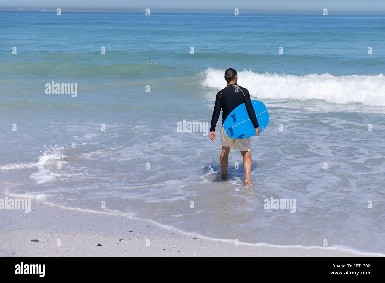 Homme caucasien senior tenant une planche de surf à la plage. Banque D'Images