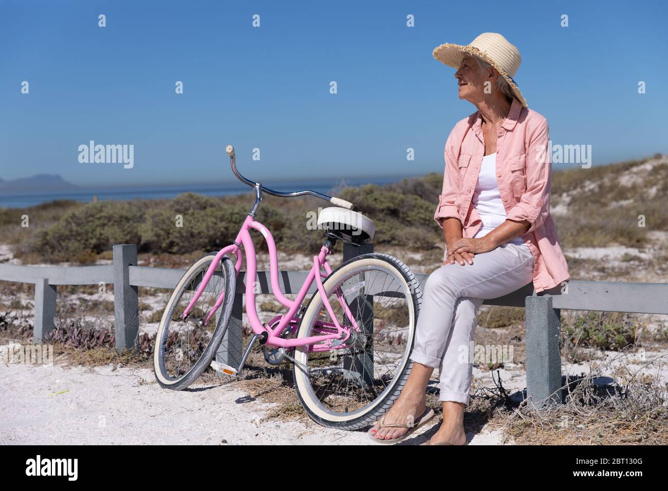 Femme de race blanche sénior sur une barrière à la plage. Banque D'Images