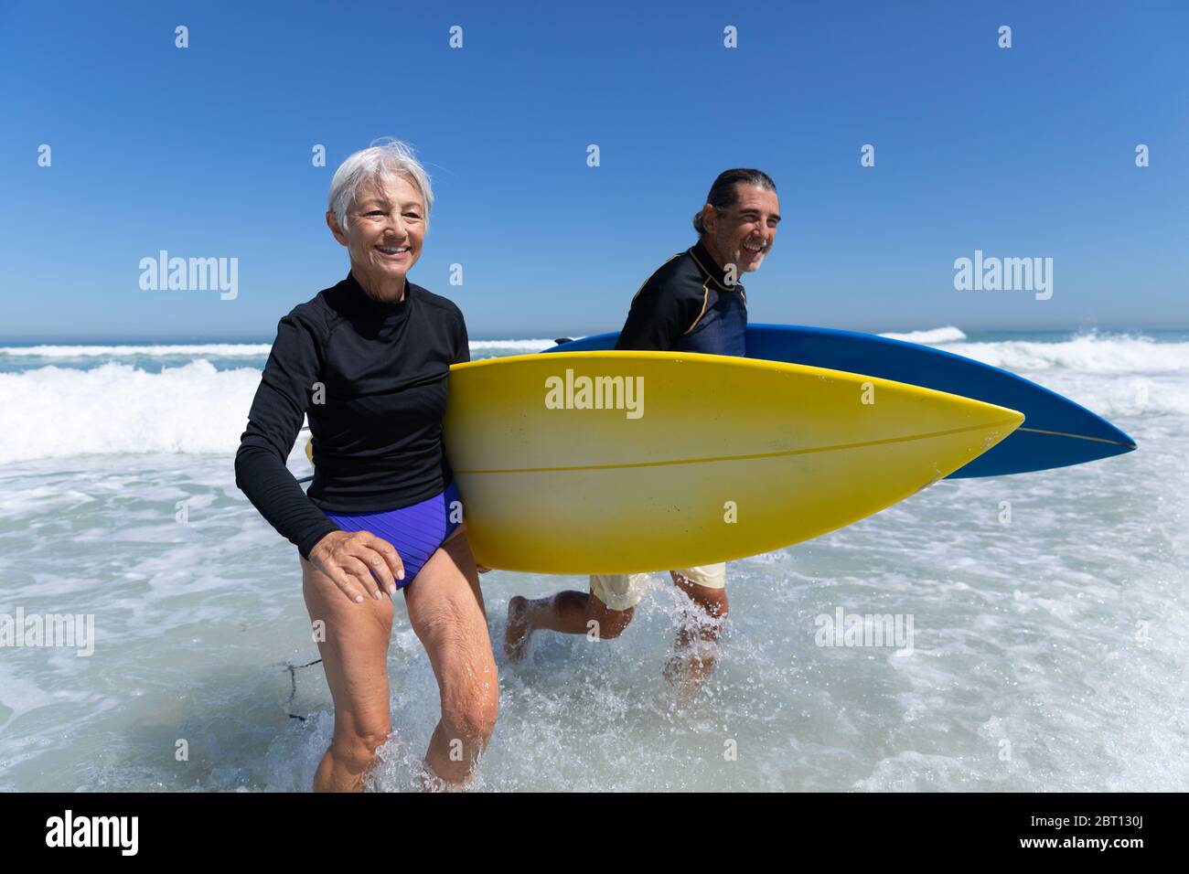 Couple caucasien senior tenant des planches de surf à la plage. Banque D'Images