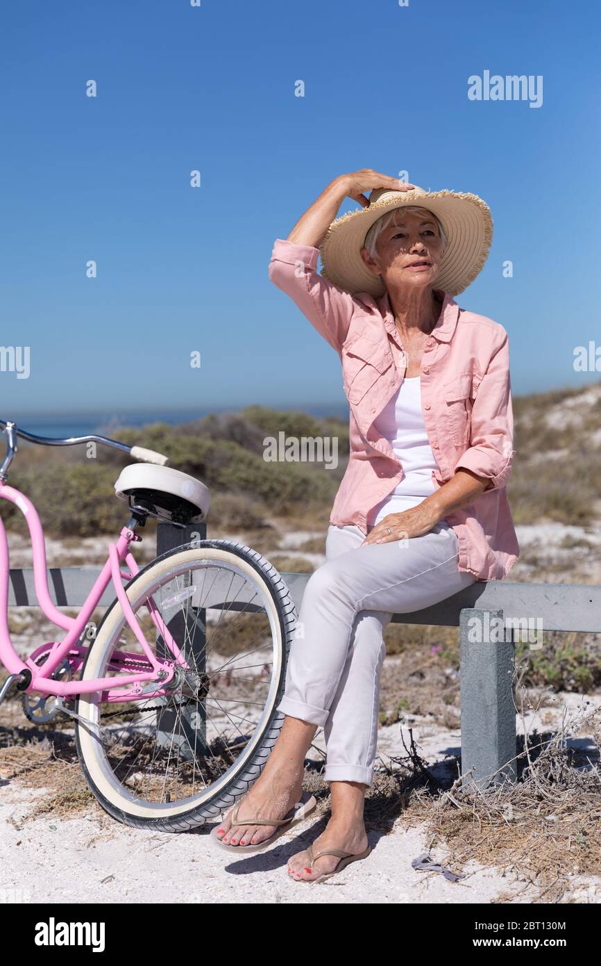 Femme de race blanche sénior sur une barrière à la plage. Banque D'Images