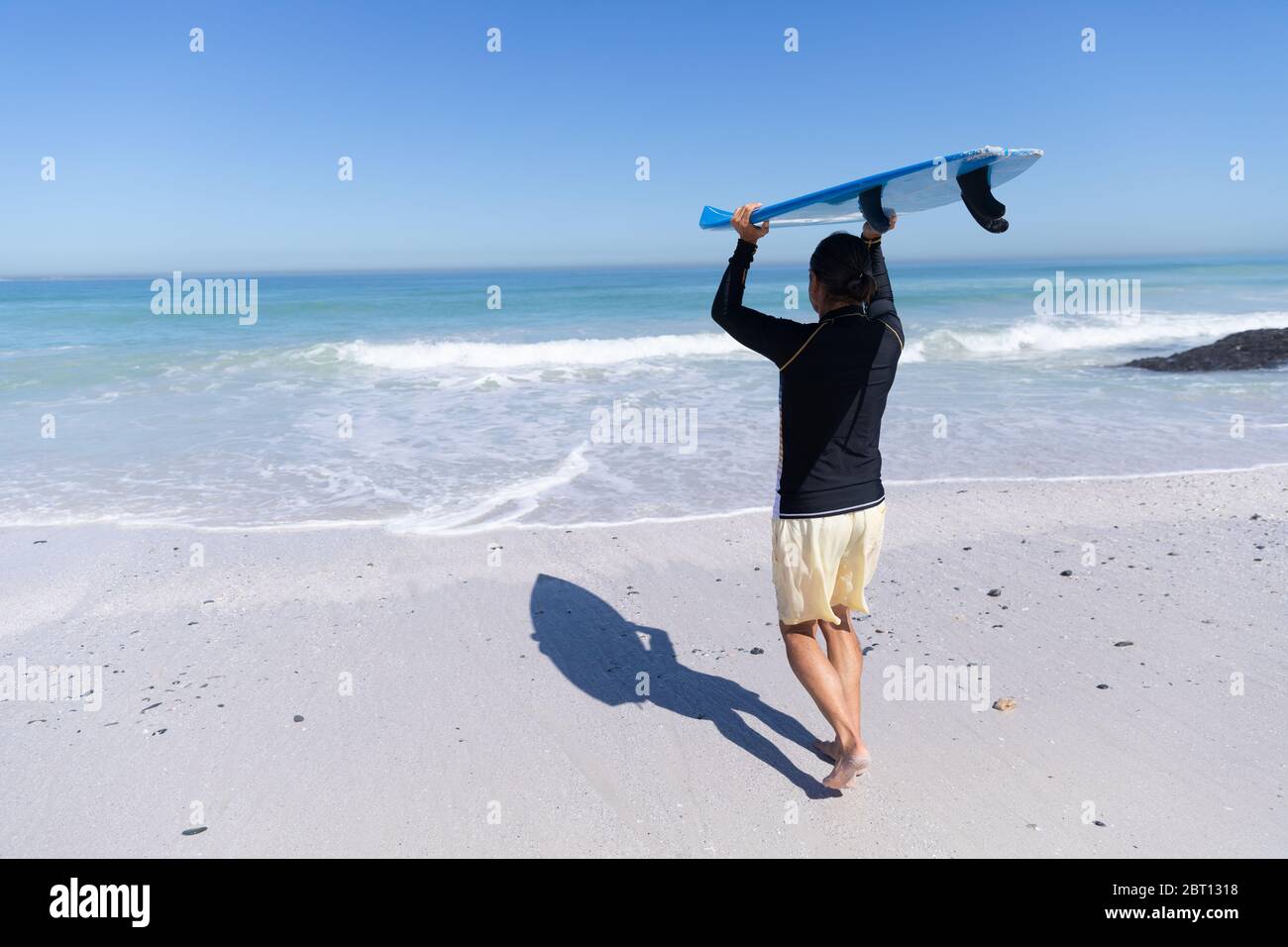 Homme caucasien senior tenant une planche de surf à la plage. Banque D'Images