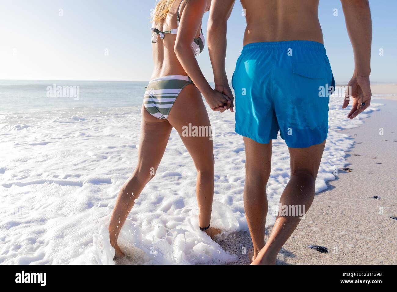 Couple caucasien debout dans l'eau à la plage. Banque D'Images