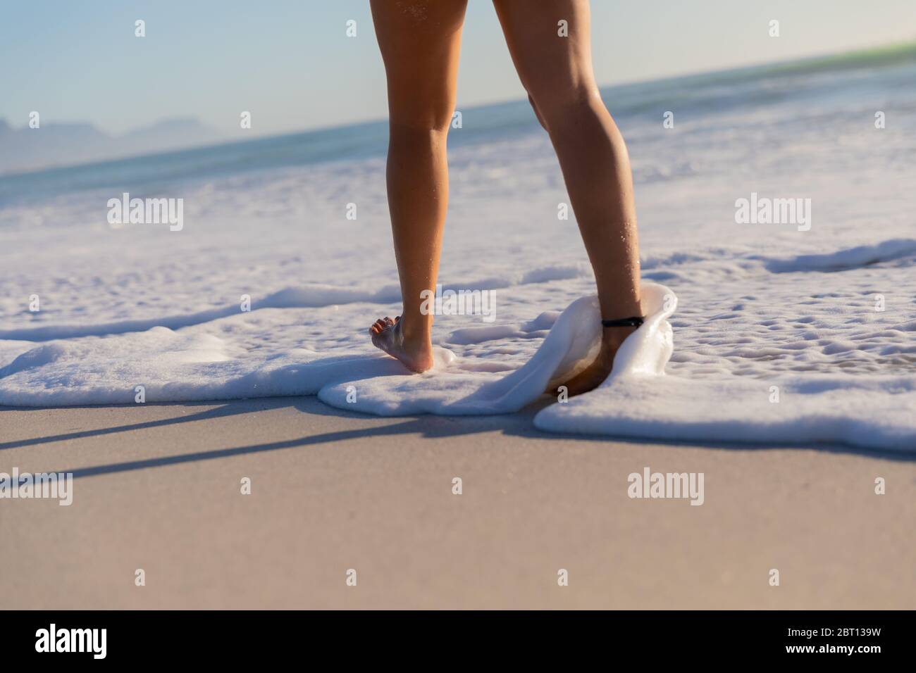 Femme caucasienne marchant vers la mer à la plage Banque D'Images