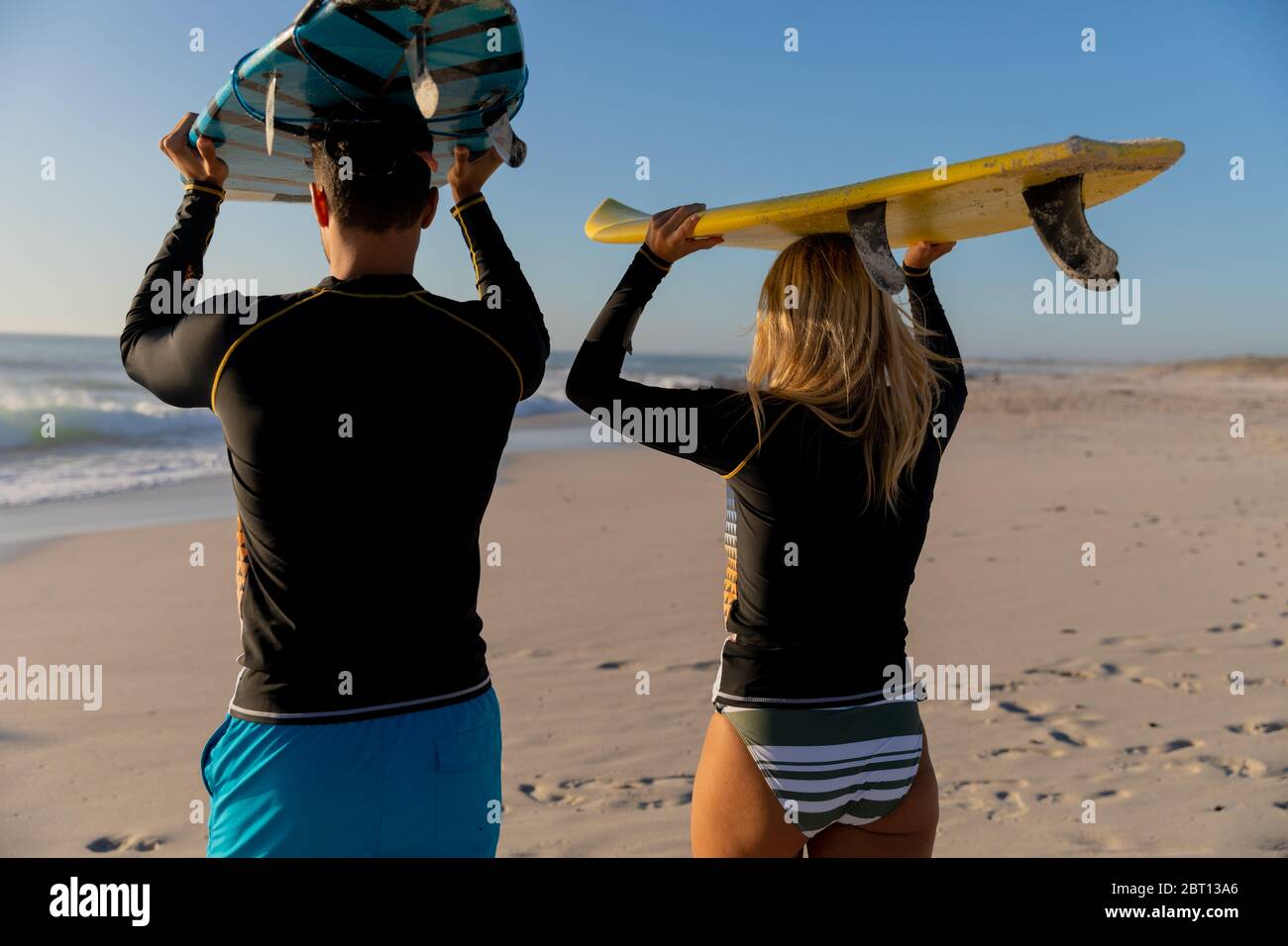Couple caucasien tenant des planches de surf à la plage. Banque D'Images