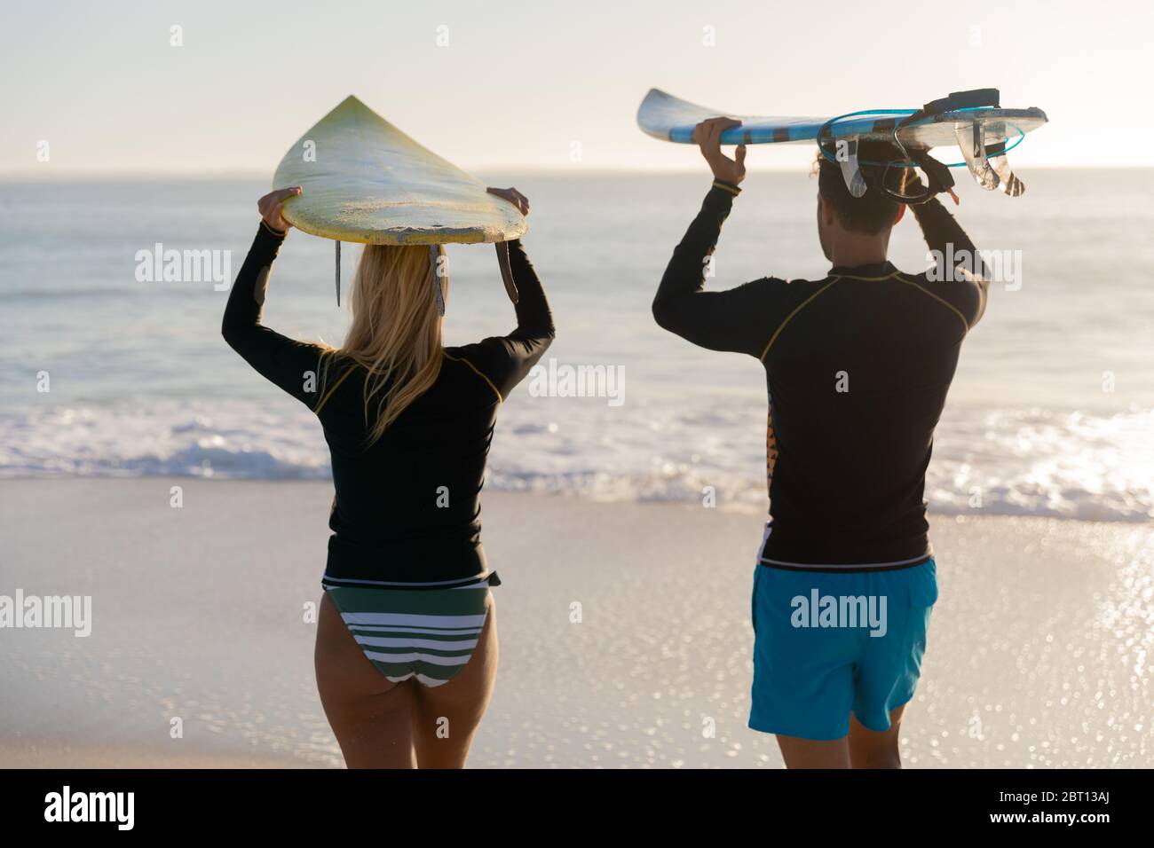 Couple caucasien tenant des planches de surf à la plage. Banque D'Images