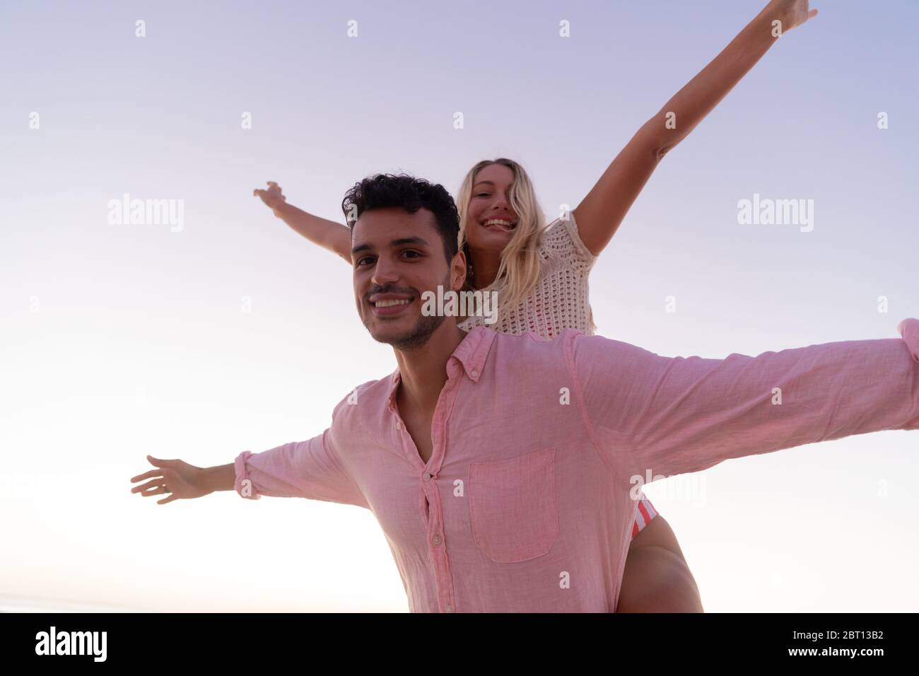 Couple caucasien appréciant le temps à la plage pendant le coucher du soleil Banque D'Images