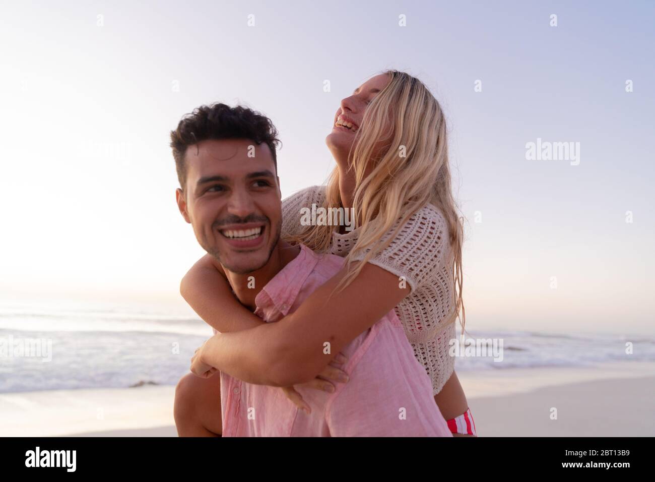 Couple caucasien appréciant le temps à la plage pendant le coucher du soleil Banque D'Images