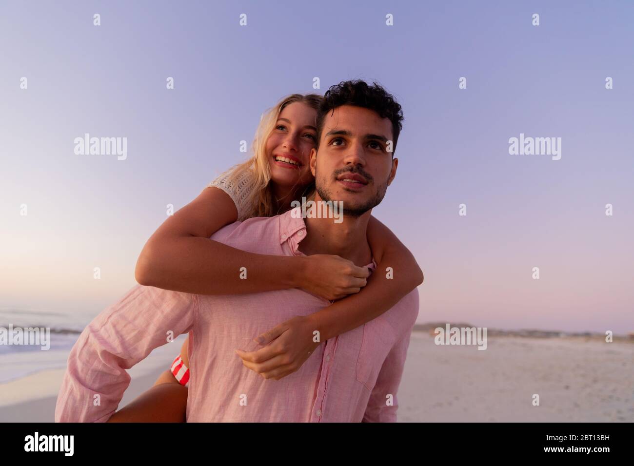 Couple caucasien appréciant le temps à la plage pendant le coucher du soleil Banque D'Images