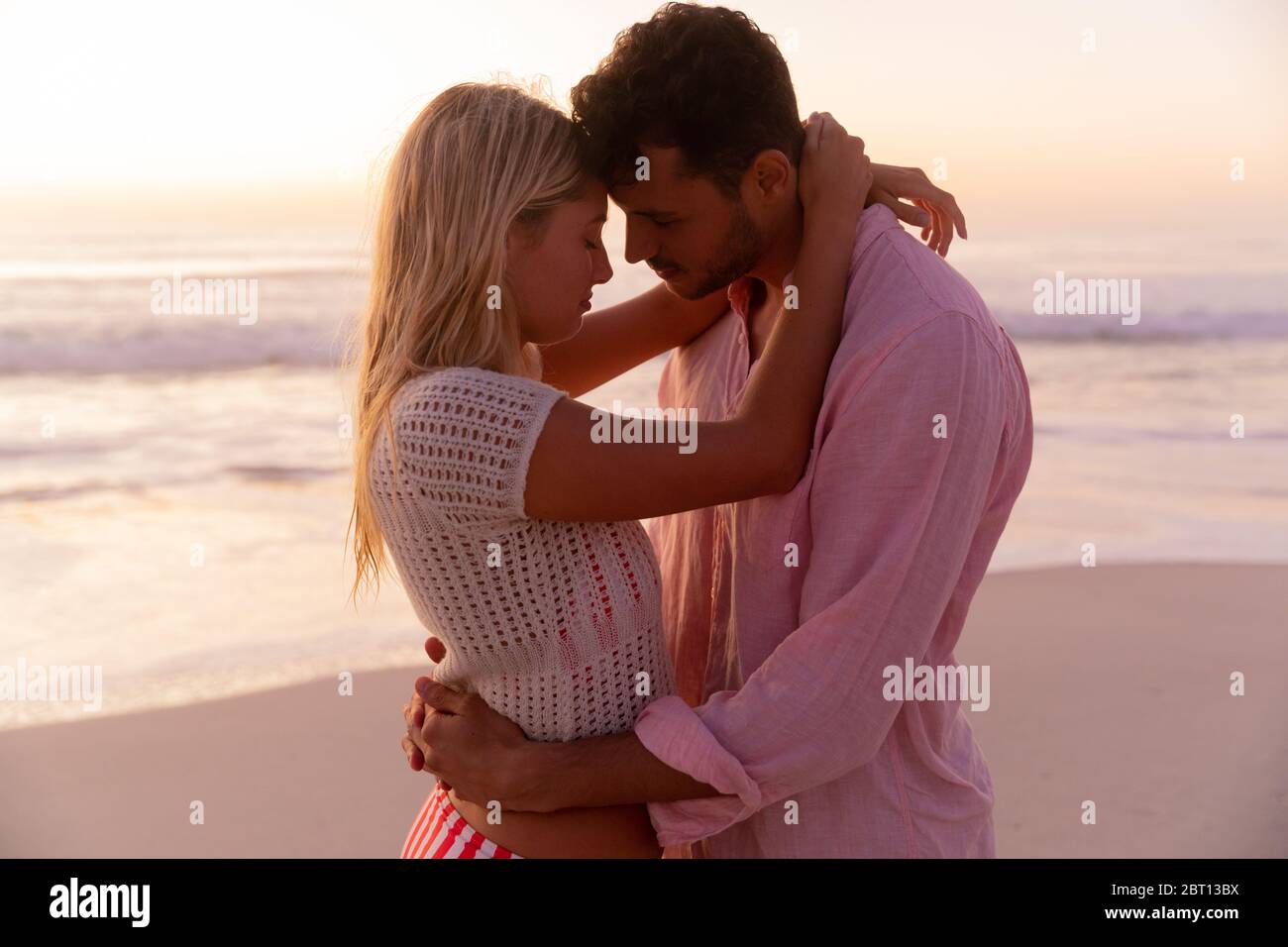 Couple caucasien appréciant le temps à la plage pendant le coucher du soleil Banque D'Images