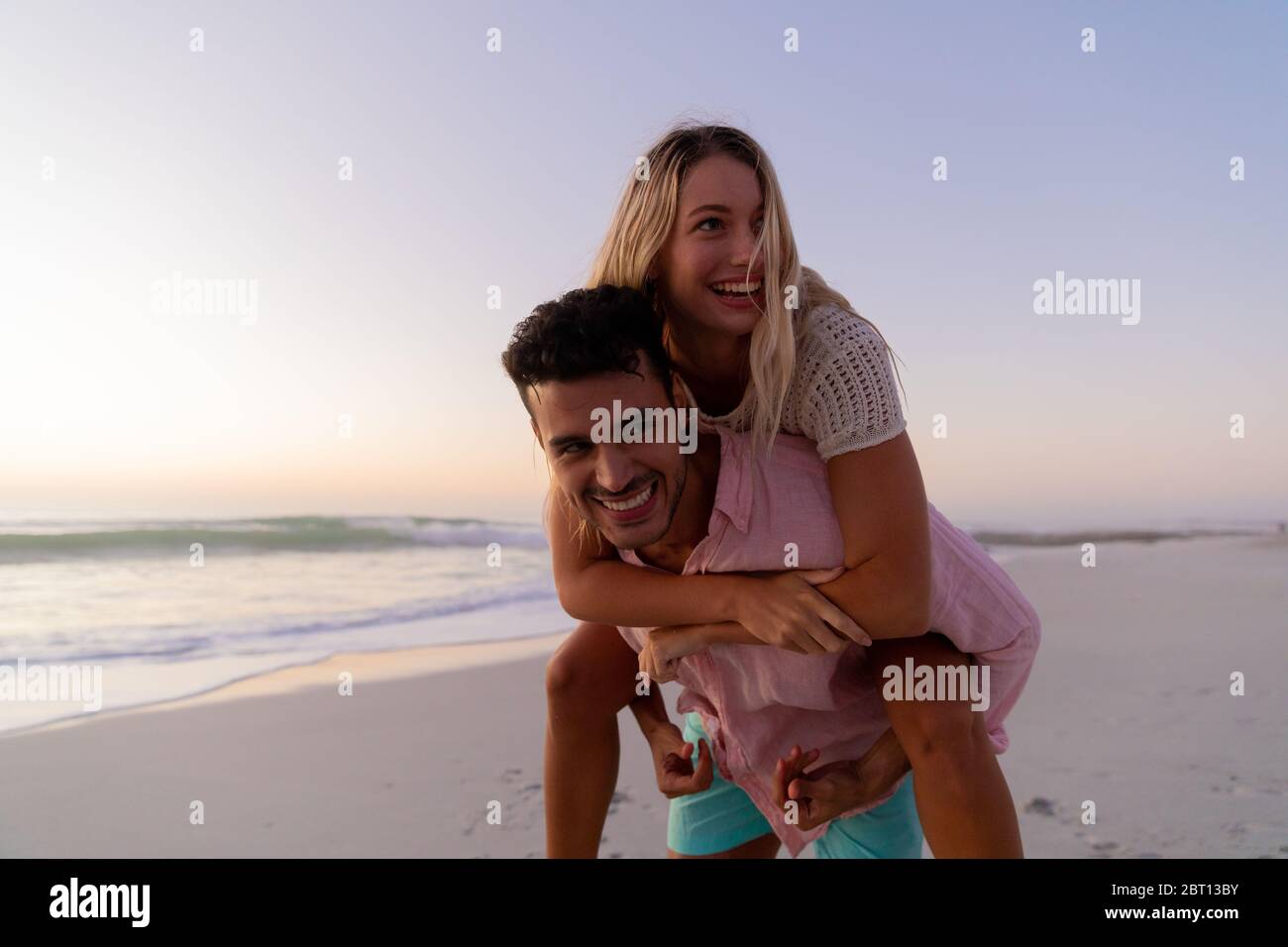 Couple caucasien appréciant le temps à la plage pendant le coucher du soleil Banque D'Images