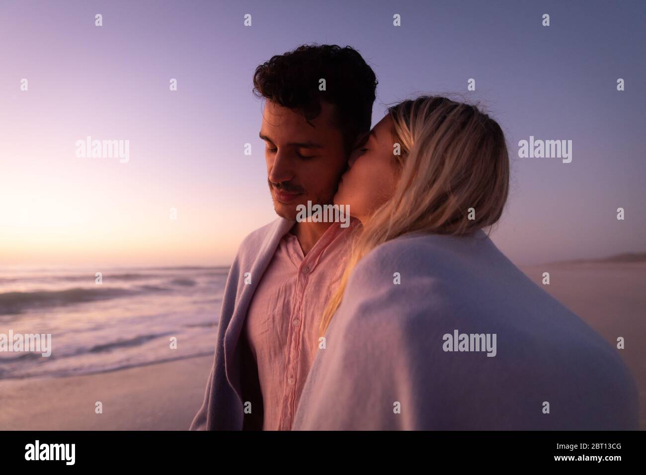 Couple caucasien appréciant le temps à la plage pendant le coucher du soleil Banque D'Images