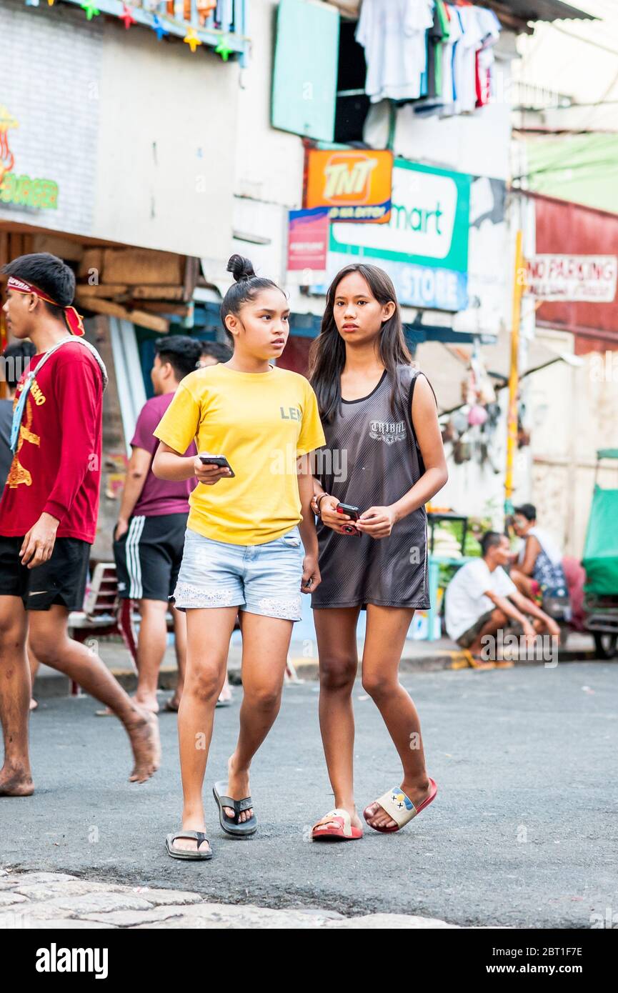 Photos spontanées de familles et d'enfants qui font leurs affaires quotidiennes dans la vieille ville fortifiée d'Intramurous Manille, aux Philippines. Banque D'Images