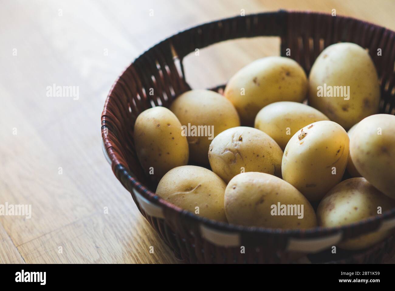 Pommes de terre dans un panier en osier. Tubercules de pommes de terre en osier et dispersés sur la table. Récolte de pommes de terre. Légumes pour une alimentation saine. Banque D'Images